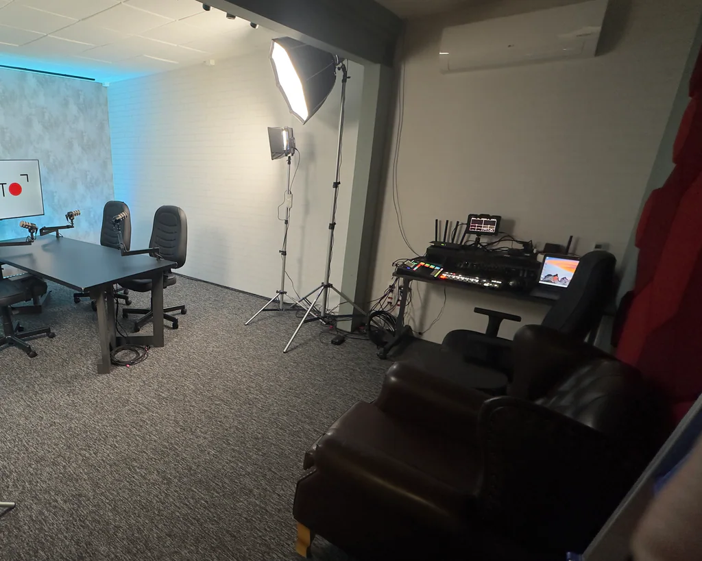 Estúdio da Capto com mesa de gravação, softbox de iluminação e rack de transmissão com monitor de vídeo