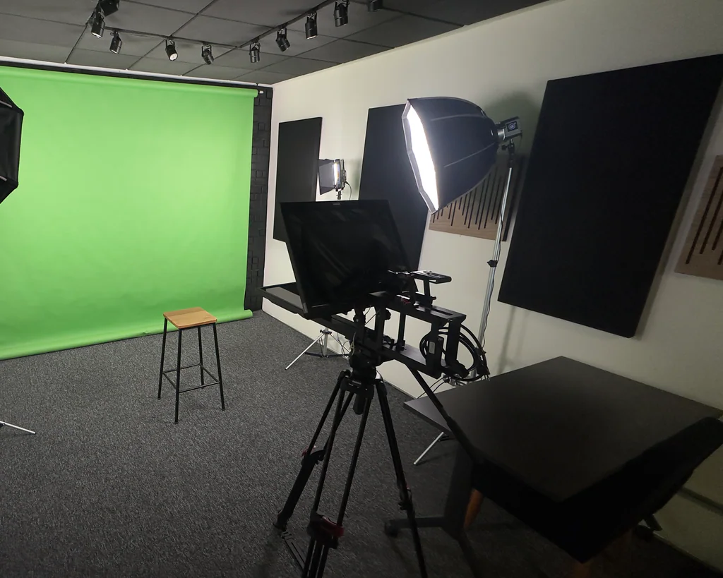 Estúdio com fundo chroma key verde, teleprompter, softbox de iluminação e mesa na Capto