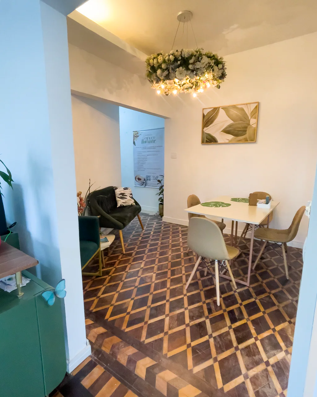 Sala de estar com lustre floral branco e sofá verde no Espaço Iluminar