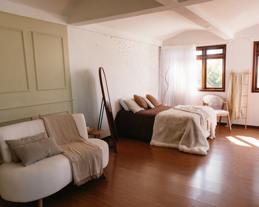 Cenário de quarto com cama, poltrona, parede de tijolos e janela no Studio Jardim Secreto
