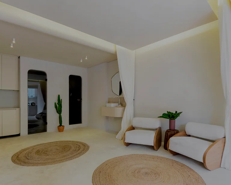 Ambiente amplo do ONCÈ Studio com luz solar entrando em diagonal, poltrona bege e copa ao fundo