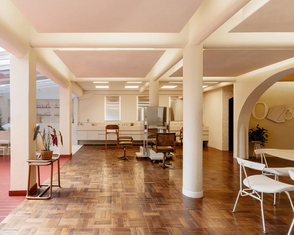 Sala de estar do ONCÈ Studio com poltronas brancas de madeira, cortina, espelho e cactos decorativos