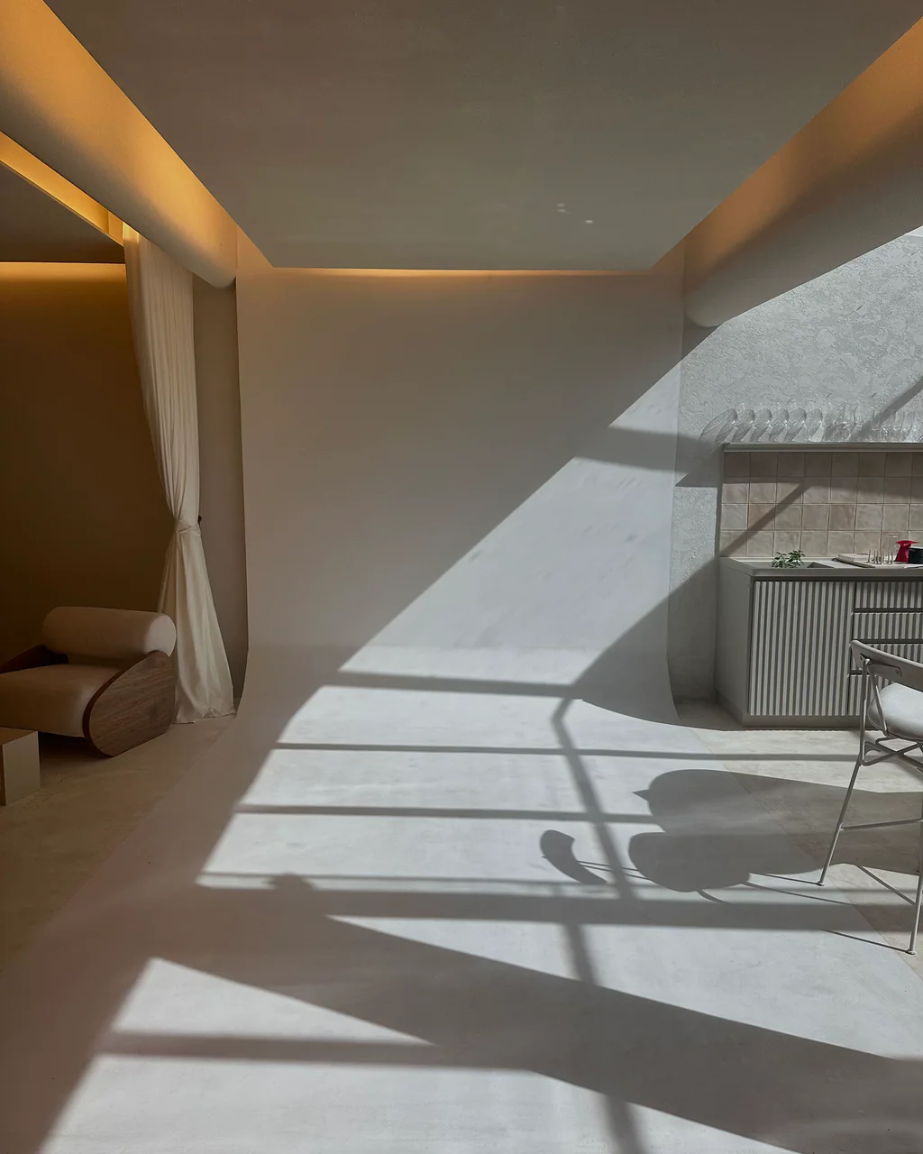 Área de estúdio do ONCÈ Studio com sombra projetada de grade de luz sobre piso claro e balcão ao fundo