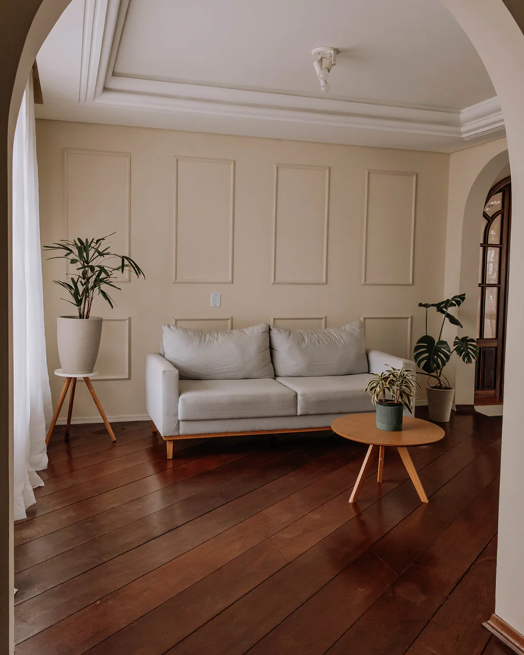 Sala vista através de um arco, com sofá, mesa de centro e plantas no Studio Keeper